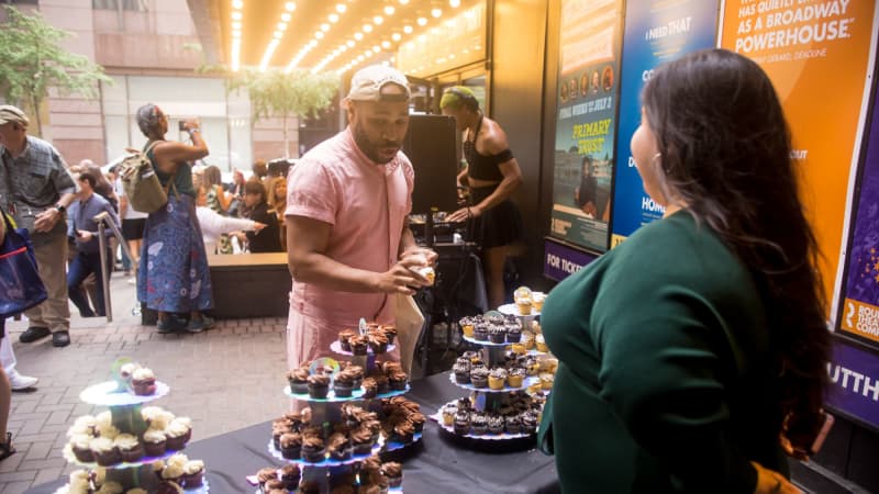 A person observes a table with several tiered stands of chocolate and vanilla cupcakes.
