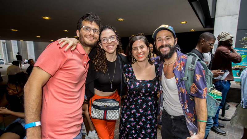 A group of four people, including musician Luke Wygodny, put their arms around each other and smile for a photo outside the theater.