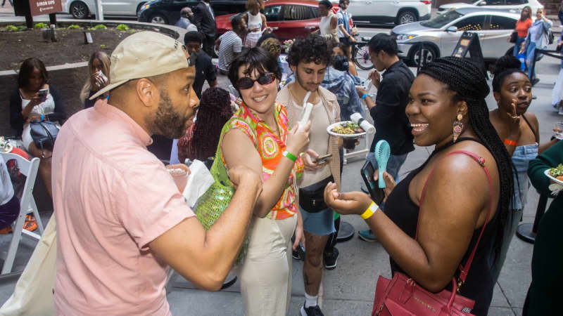 A group of people talk and laugh among a crowded patio of theatregoers.