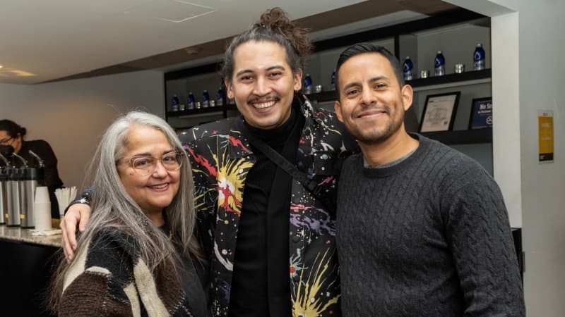 Director David Mendizábal stands with their arms around a man and a woman as the all smile cheerfully for a photo.