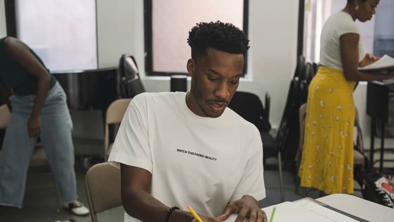 Playwright York Walker taking notes at a table in the rehearsal studio.