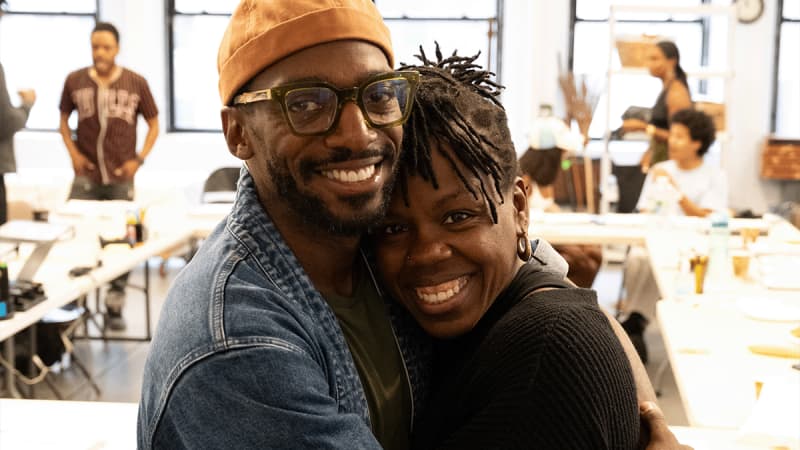 Actors Daniel J. Watts and Ngozy Anyanwu hug each other in the rehearsal studio.