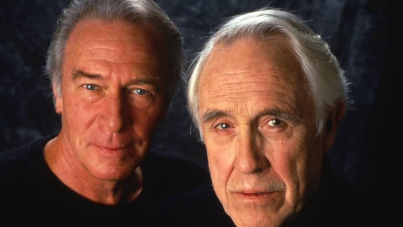 Christopher Plummer and Jason Robards Jr. both facing the camera with a dark background. Photo is from the shoulders up.