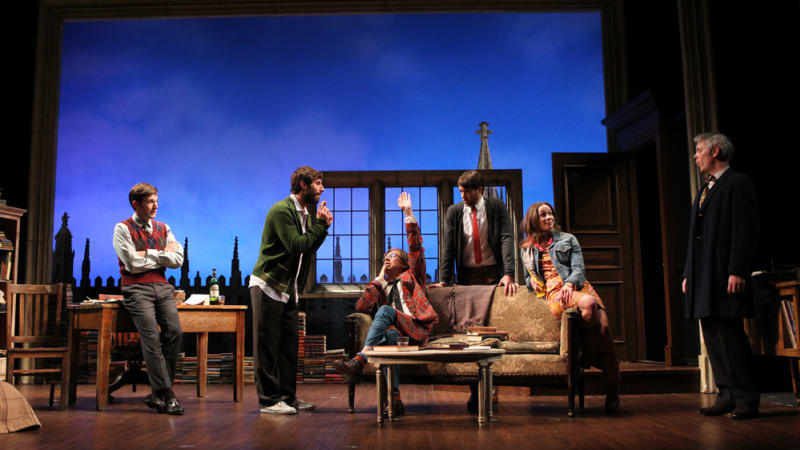 A group of mean in what seems to be a loft or office looking over a skyline. 