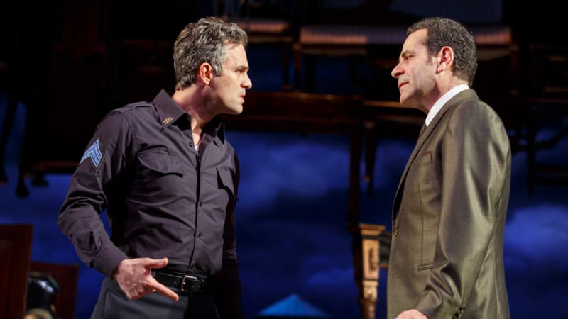 An angry man in a police uniform talks to a man in a shiny olive green suit.
