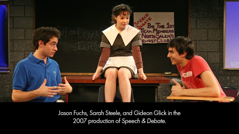 Production photo from SPEECH AND DEBATE. Two teenage boys sit in school desk chairs while a teenage girl wearing a dress with a large white collar and white apron sits on a table.
