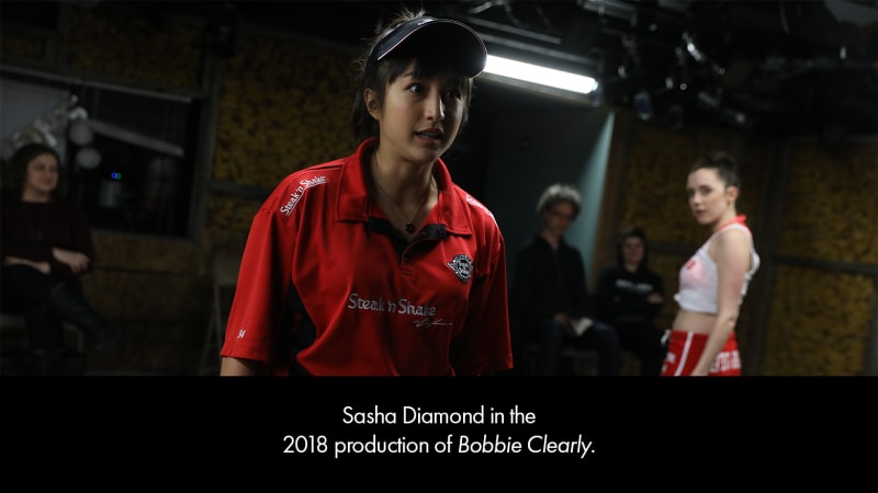 Sasha Diamond in the 2018 production of BOBBIE CLEARLY. A medium-skinned teenage girl wearing a red fast-food uniform.