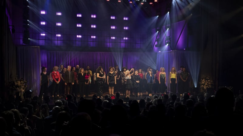A group of performers all on stage under the lights bowing to the crowd and thanking them. 