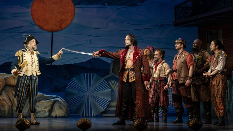 An older man in a general's uniform holds his finger to the point of a sword being held by a pirate in a long, lavish red robe. A group of rag-tag pirates stand behind them watching the encounter.