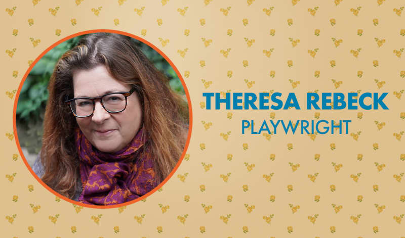 Headshot of Theresa Rebeck with brown hair and glasses in an orange frame and a floral wallpaper background. 