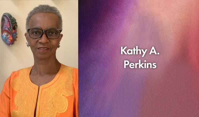 Kathy A. Perkins is a Black woman with short gray hair, glasses, silver earrings, and a bright orange shirt.