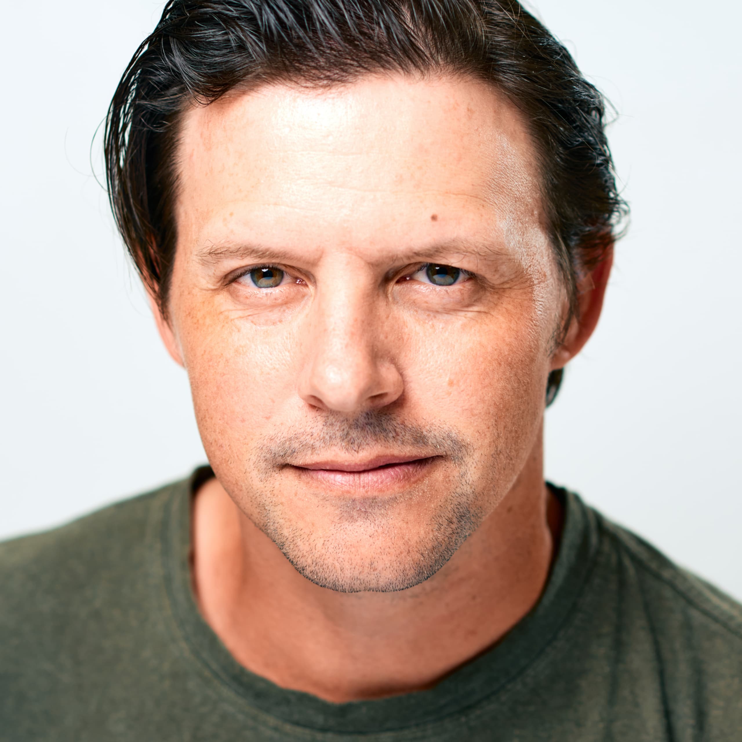Gareth has light skin, dark eyes, dark bwon hair, and wears a dark green t-shirt.