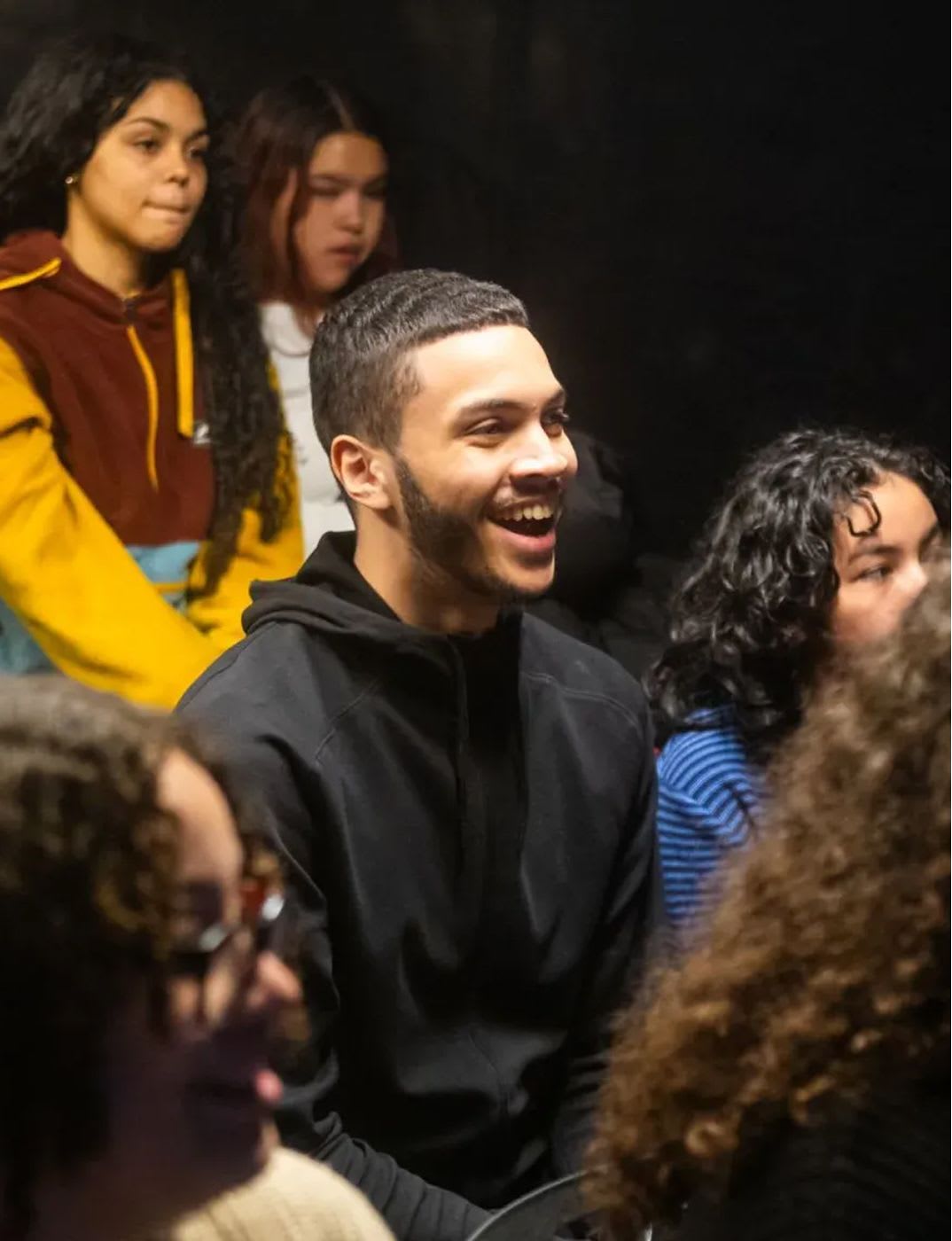 Students participate in a Roundabout Theatre Company workshop, seated in a group and engaged in a live theatre learning experience.