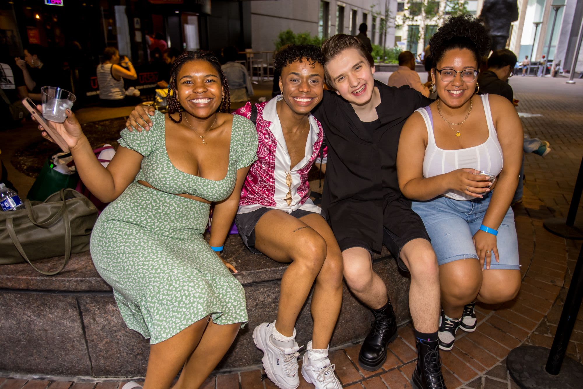 Four guests sit together and smile during a Black Theatre Night outdoor reception for Primary Trust at Roundabout Theatre Company.