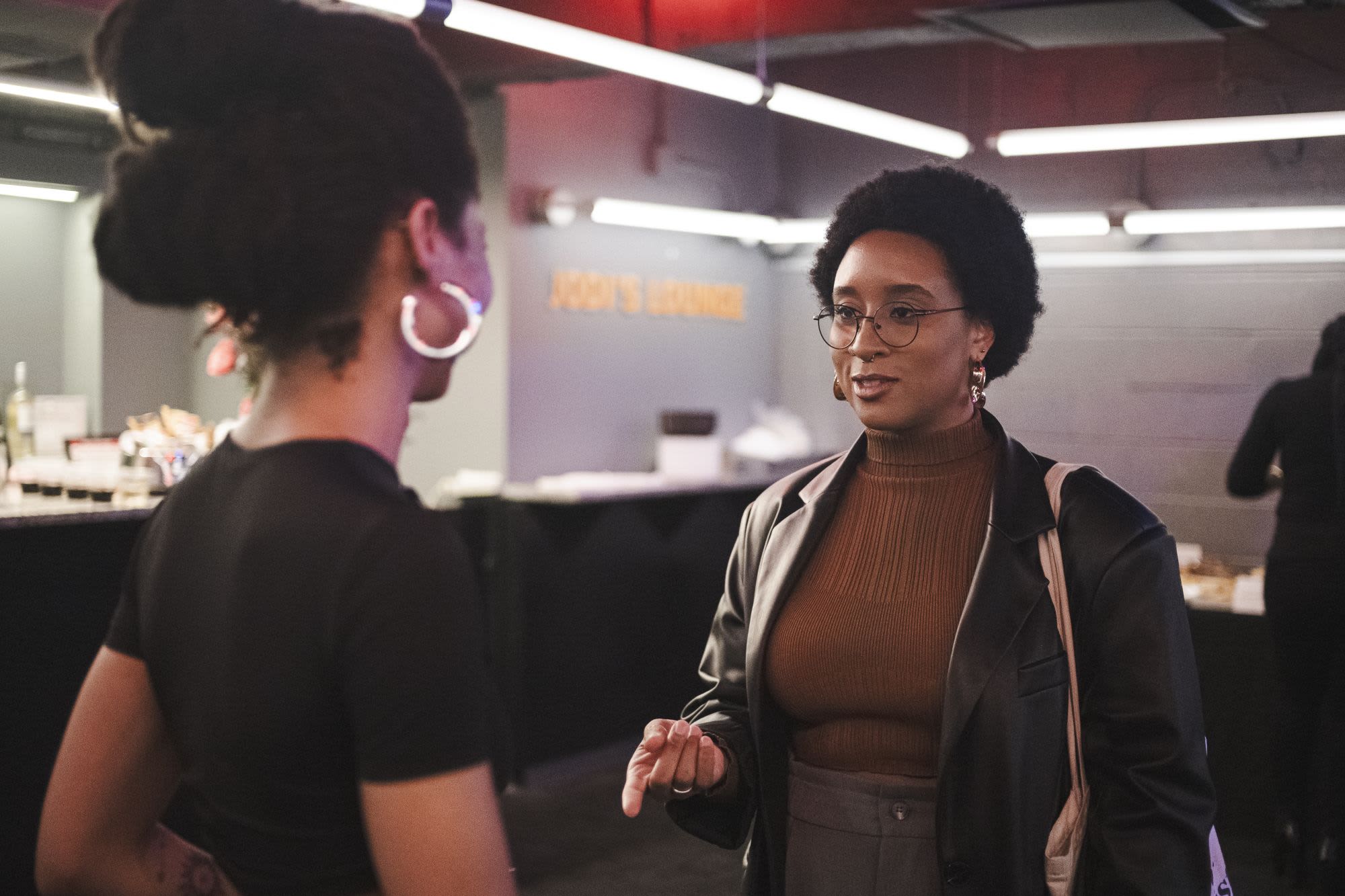 Two guests converse at a Black Theatre Night community event at Roundabout Theatre Company, near a lounge area in the background.

