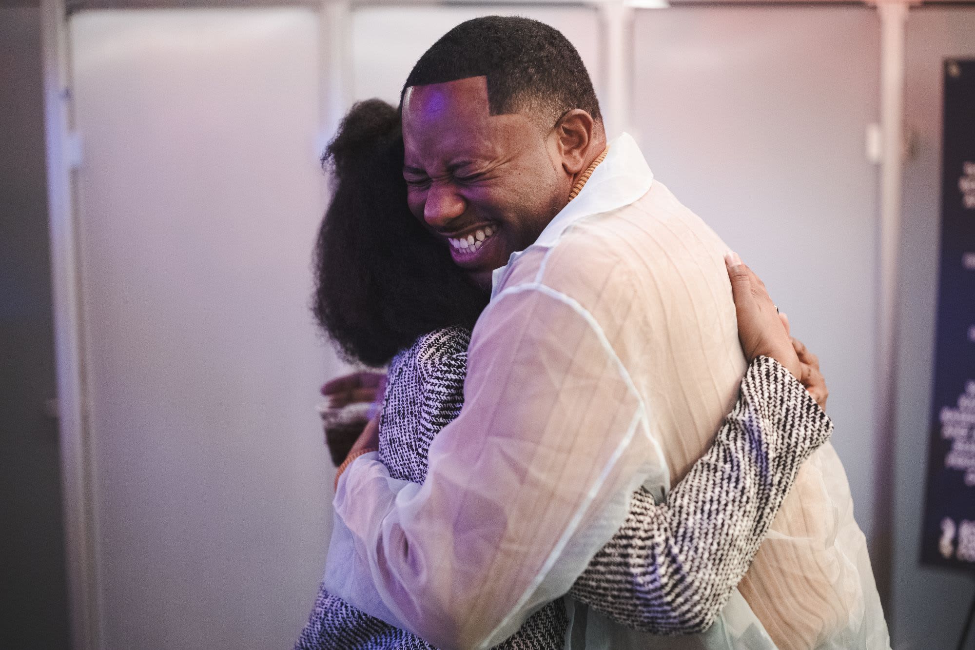 Two guests share a warm embrace at a Roundabout Theatre Company Black Theatre Night community event.