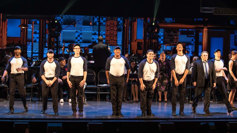 The cast of DAMN YANKEES at curtain call. A line of men in baseball tees and hats takes their bow.