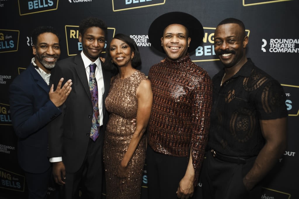 A group of people in formal attire pose on the red carpet.