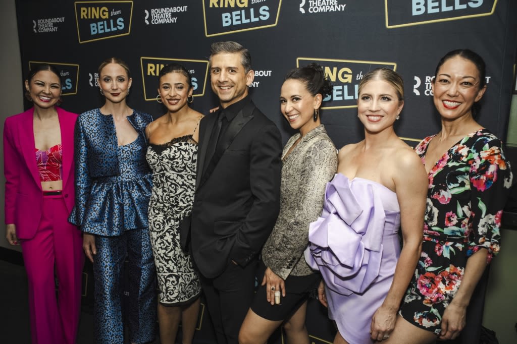 A group of people in formal attire pose on the red carpet.