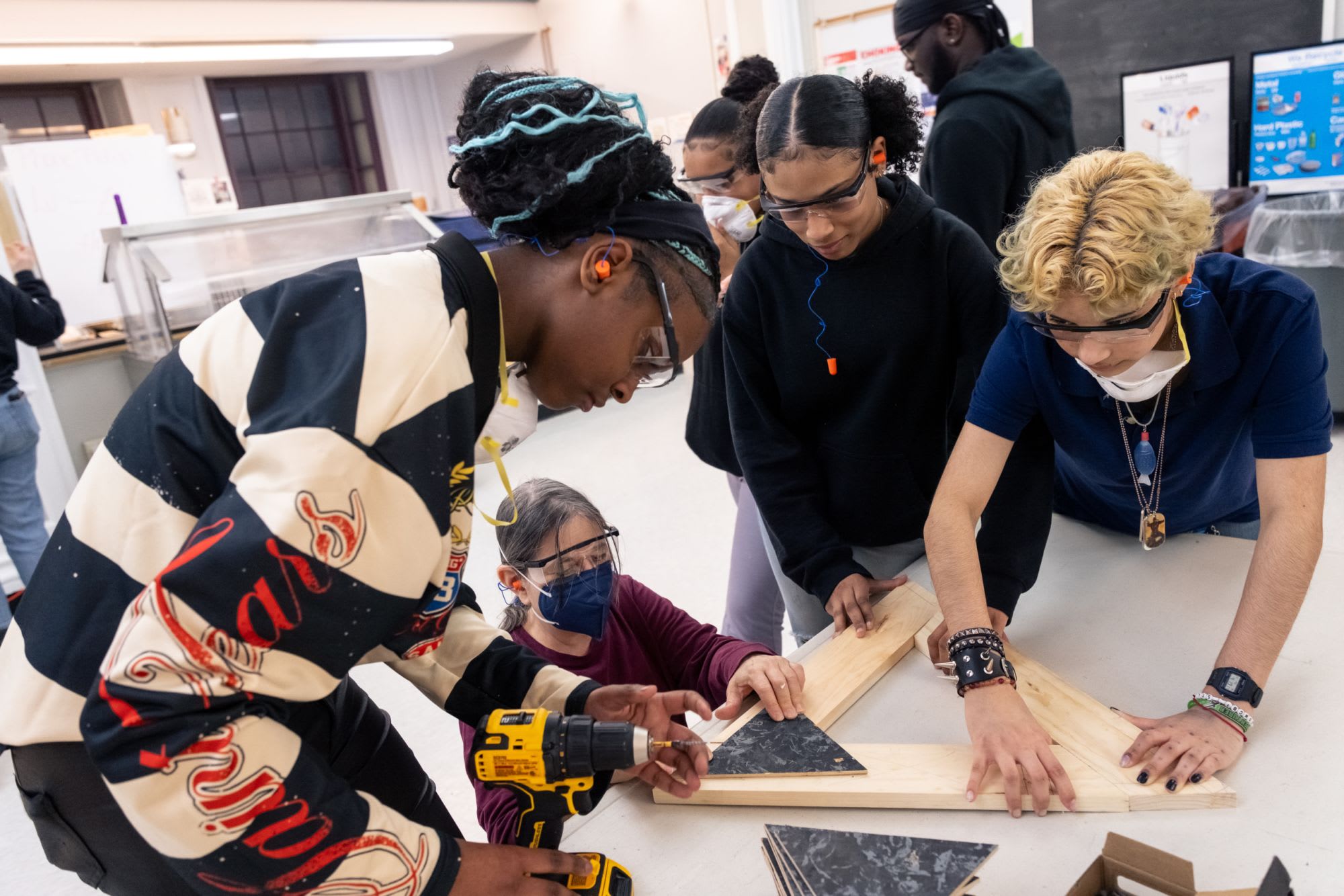 A group of students collaborate on a woodworking project.