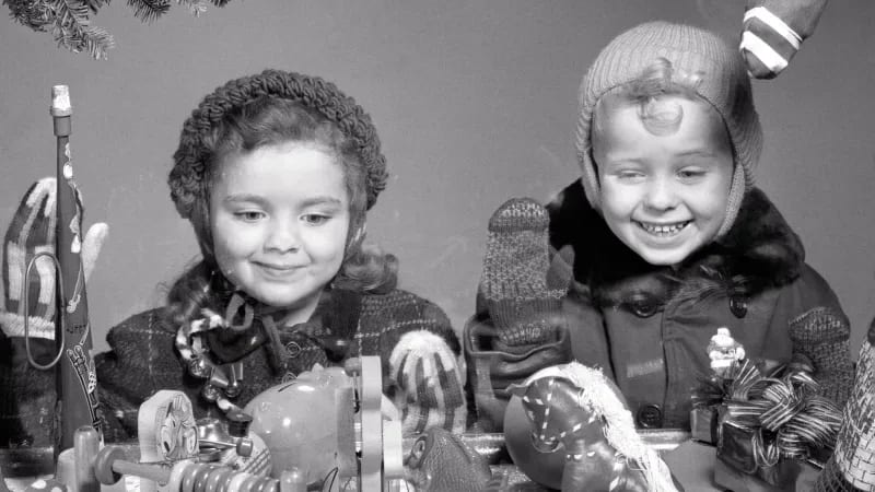 Children in the 1950s look at a Christmas display of toys.