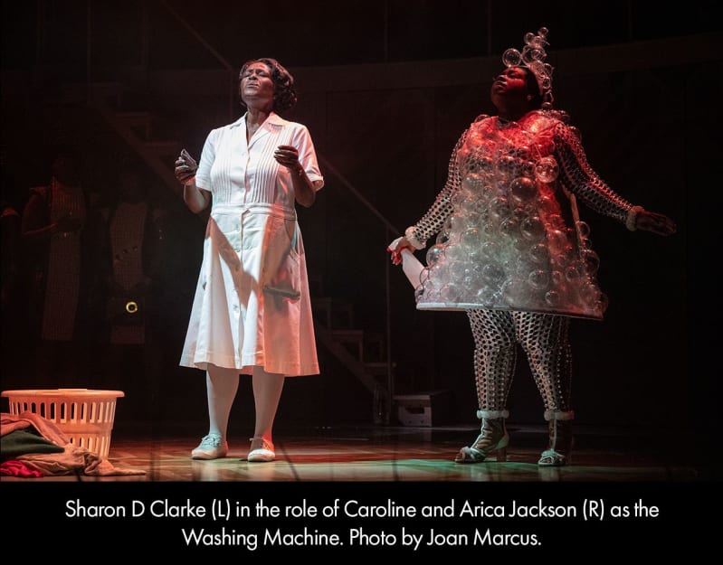 Sharon D. Clarke in the role of Caroline and Arica Jackson as the Washing Machine. A Black woman in a white maid’s uniform stands next to a Black woman in a dress made of bubbles.