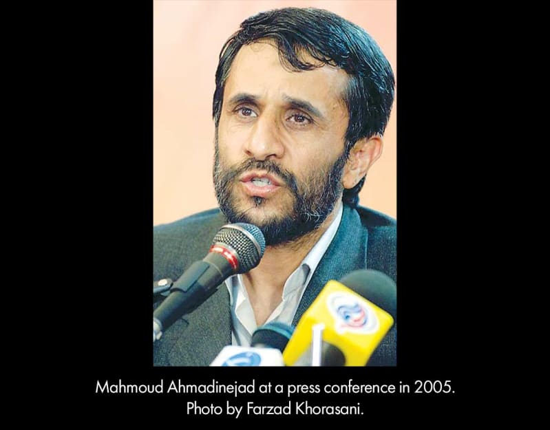 Mahmoud Ahmadinejad at a press conference in 2005. A middle-aged, light-brown skinned man with a beard speaks into microphones.