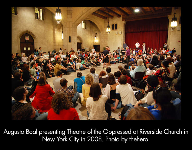  Augusto Boal presenting Theatre of the Oppressed at Riverside Church in 2008. A crowd of people sit on a church floor with people interacting in the center space.