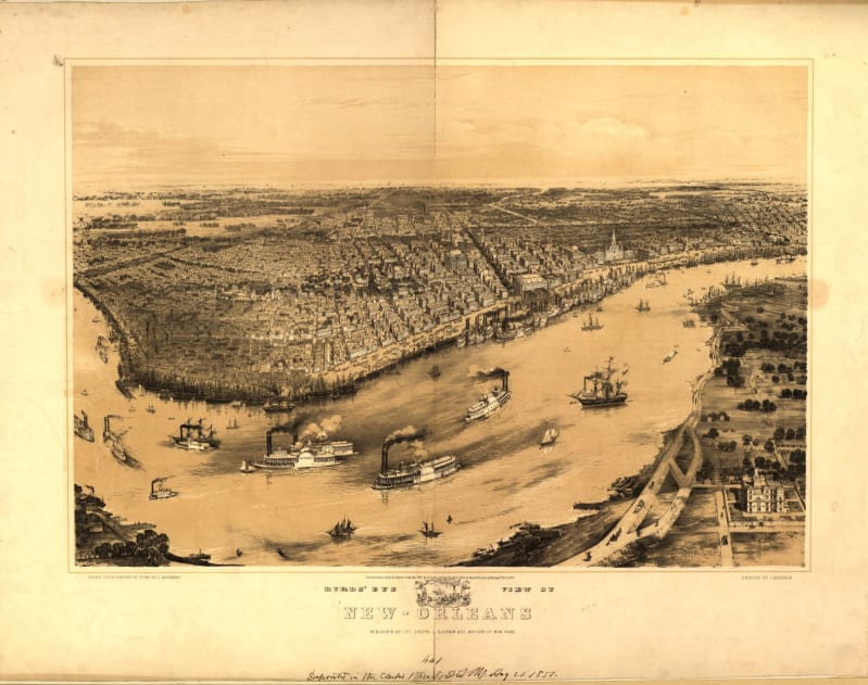 A river bend with many steamships in front of a city full of buildings, laid out on straight streets. 