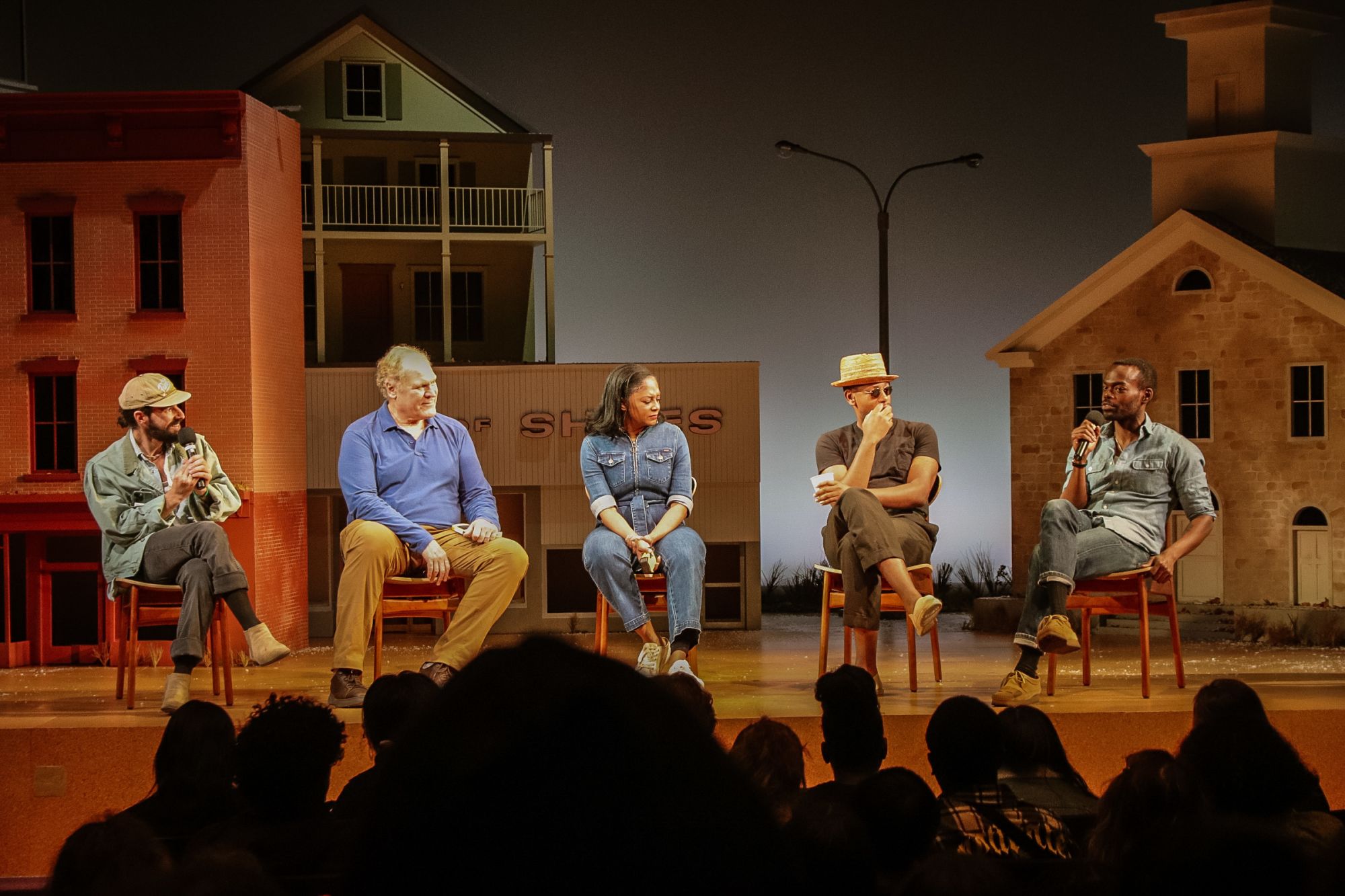 A group of actors sit on stage during a talkback.