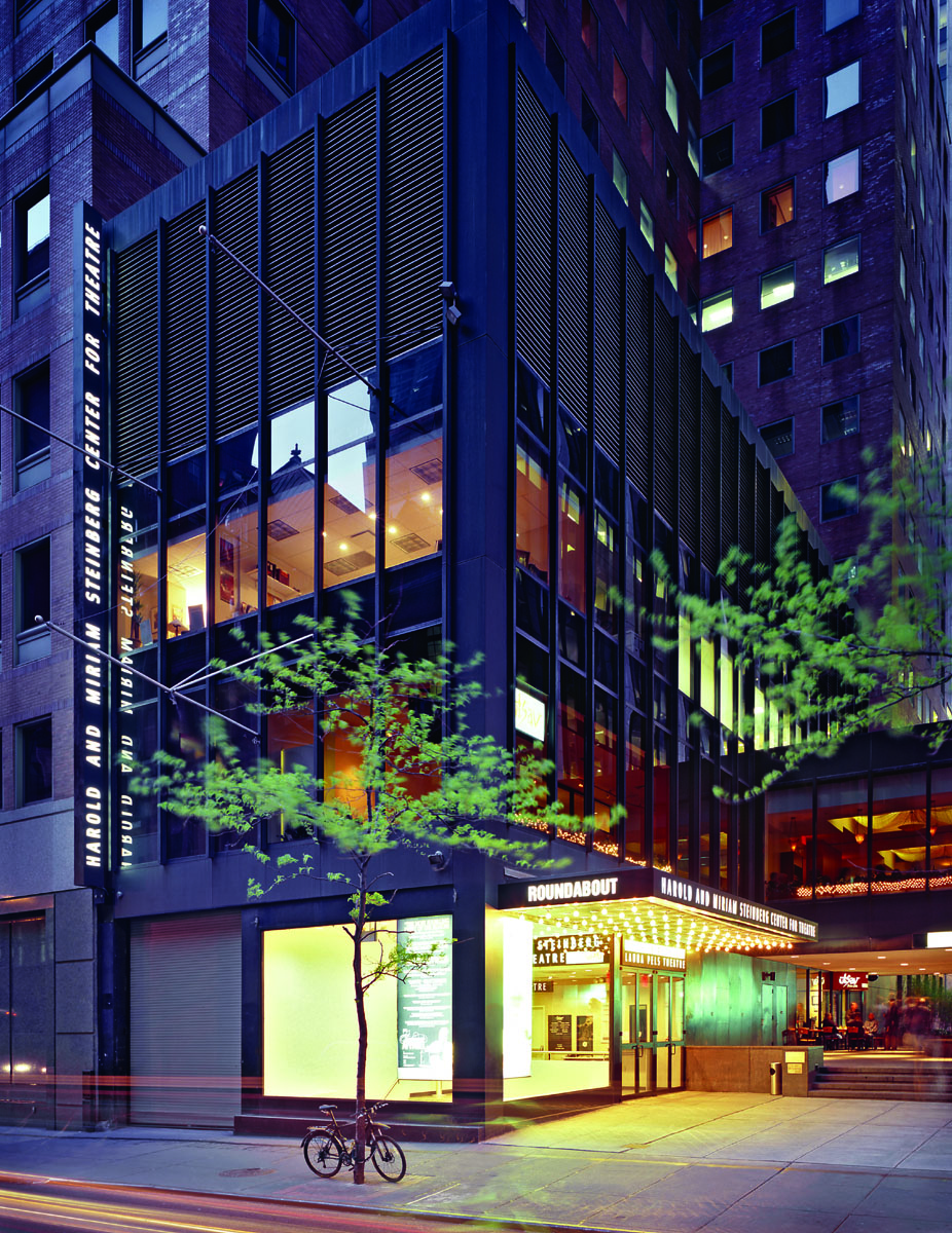 The exterior of the Harold and Miriam Steinberg Center for Theatre with the lobby lit up.