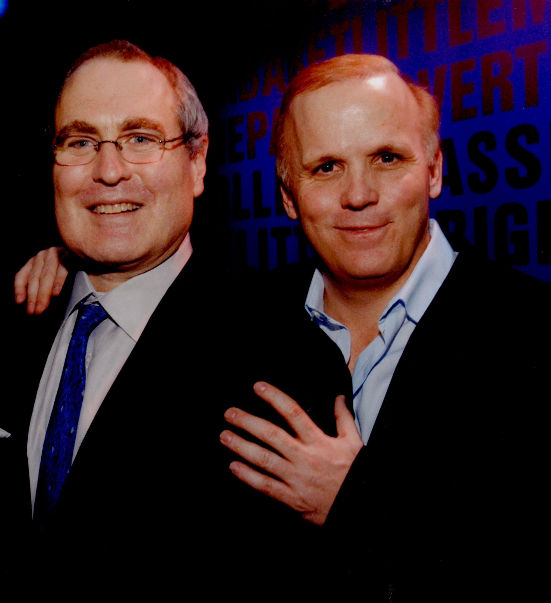 Todd Haimes (left) and Scott Ellis (right) both smiling, dressed in suits in front of a blue background.