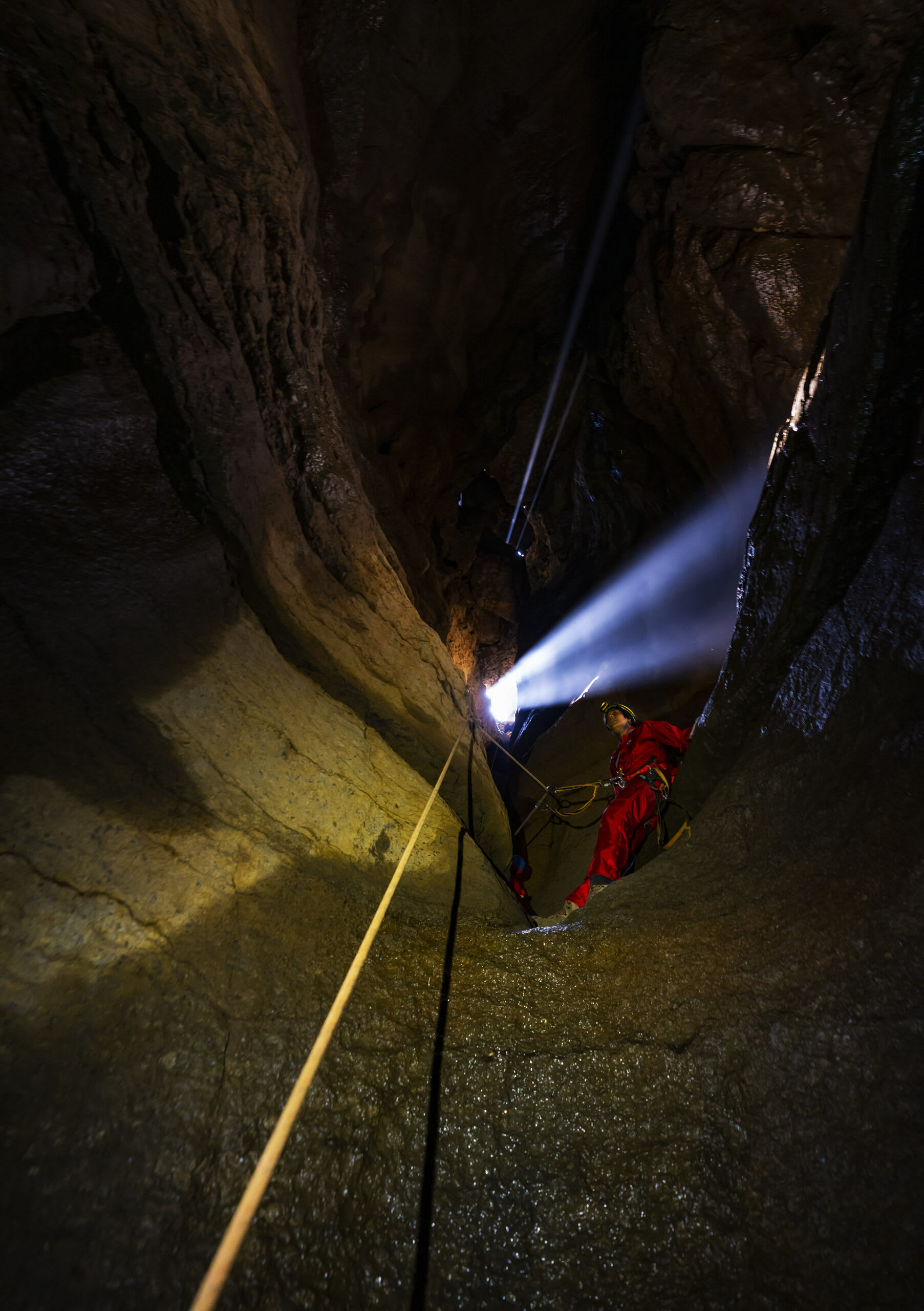 Resting on a narrow and wet ledge, the author (above) awaits her turn on the rope. In the cracks, frogs, crickets and spiders might be visible to those looking with a keen eye.