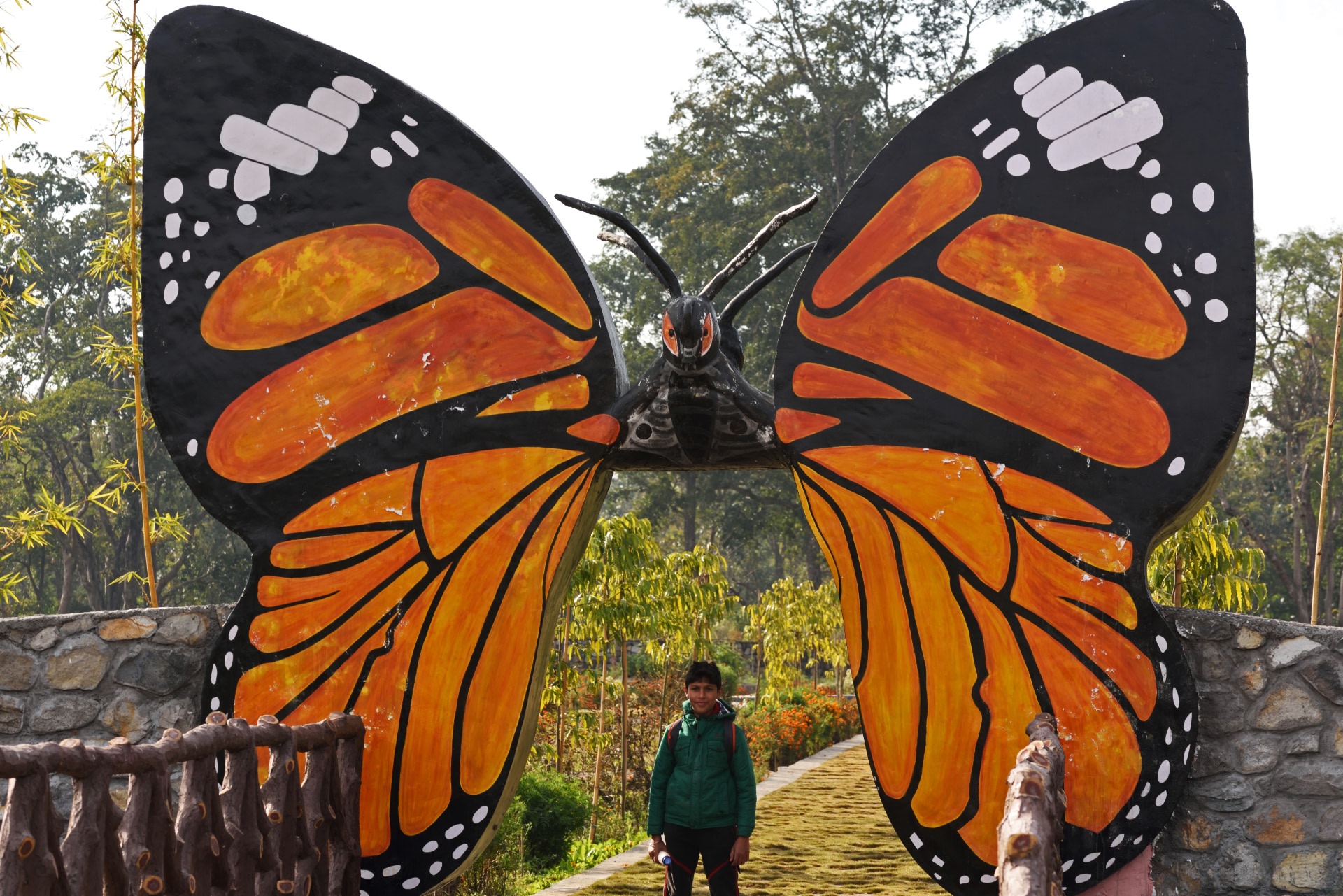 A child stands under a model of the plain tiger butterfly at the Shiwalik Butterfly Park at Lacchiwala, Dehradun.