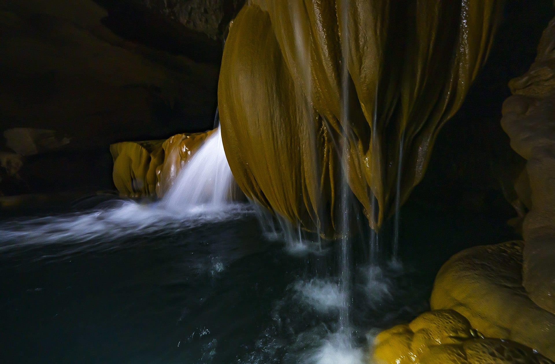 There is a surreal beauty to caves once the veil of darkness is lifted. Often hidden from human eyes in difficult-to-reach locations, witnessing them involves braving slippery slopes, belly-crawling at times through narrow passages, and wading or swimming through icy-cold, crystal clear rivers or pools of water. In river caves where there is flowing water, like the stunning Krem Chympe, we spent days exploring, water also creates stunning rimstone dams or gours. Pictured here is one of the rarer formations, that looks like a lotus, and creating waterfalls that cascade into turquoise subterranean pools. 