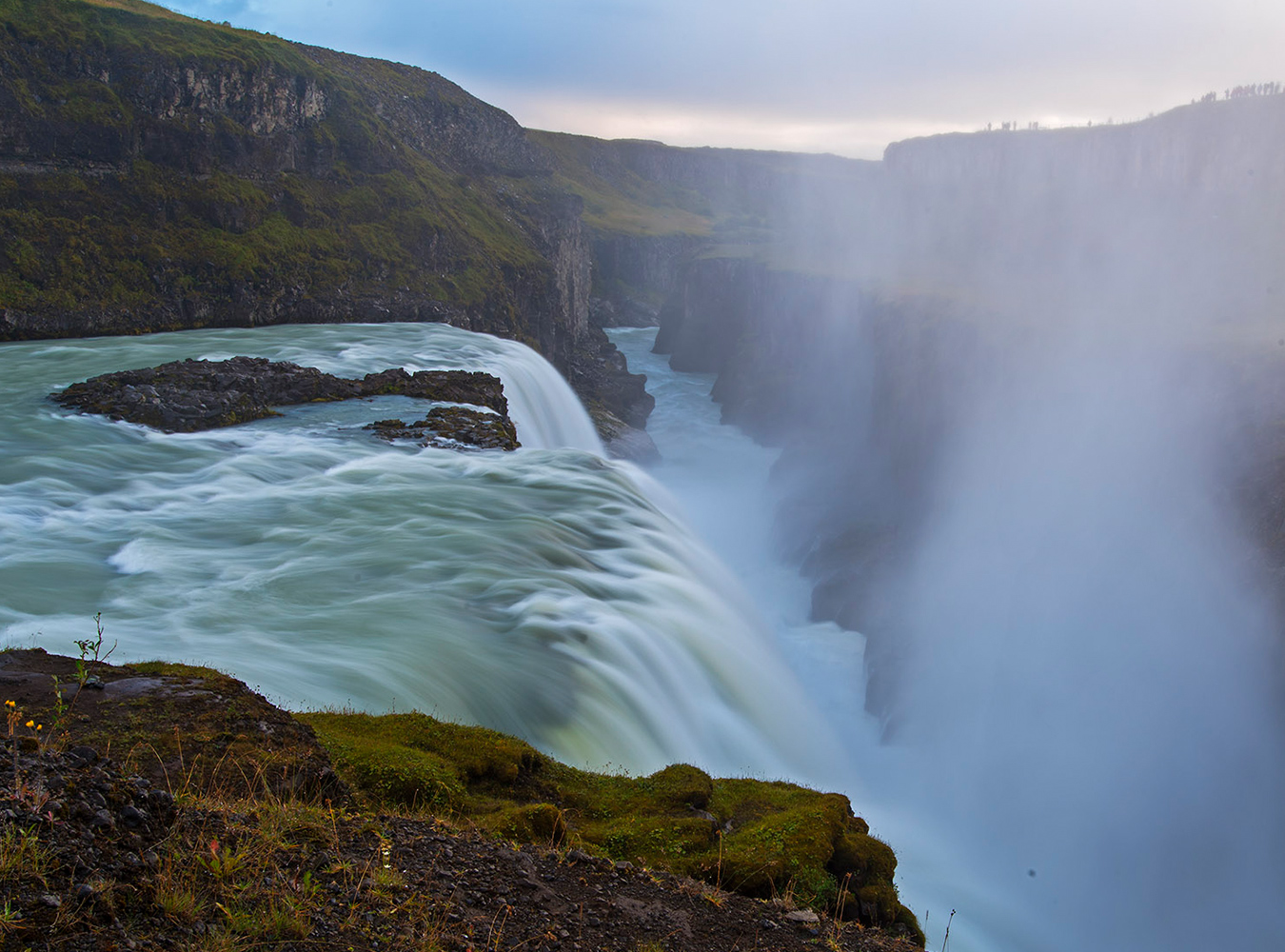 It’s a spectacular scene. From a viewing platform above, the waters of the Hvítá River, which are fed by Iceland’s second biggest glacier the Langjökull, plummet downward to create Gullfoss Waterfall. This is one of Iceland’s most famous attractions and if you are lucky and it is a sunny day, a brilliant rainbow may also be seen over the falls.

