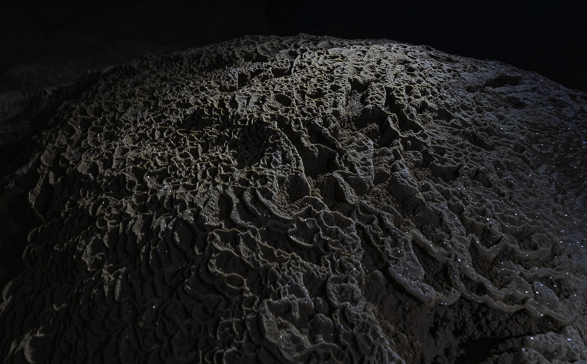 The effects of the slow action of water are everywhere, fluid movement captured in mineral deposits. Mesmerising and hypnotising, formations called speleotherms are all around us as we explore different caves. Their textures and shapes are determined by whether the acidic water has dripped, seeped, condensed, flowed, or formed ponds. After the process of erosion, as the water continues to seep in into the slowly-forming caves, it often deposits the minerals that it carries, embellishing the cave. Flowing and dripping water creates stunning patterns and formations. Cave minerals include calcite and other carbonate minerals — calcite sometimes accumulates as calcite crystals that practically glitter like jewels (above) when they catch the light.
