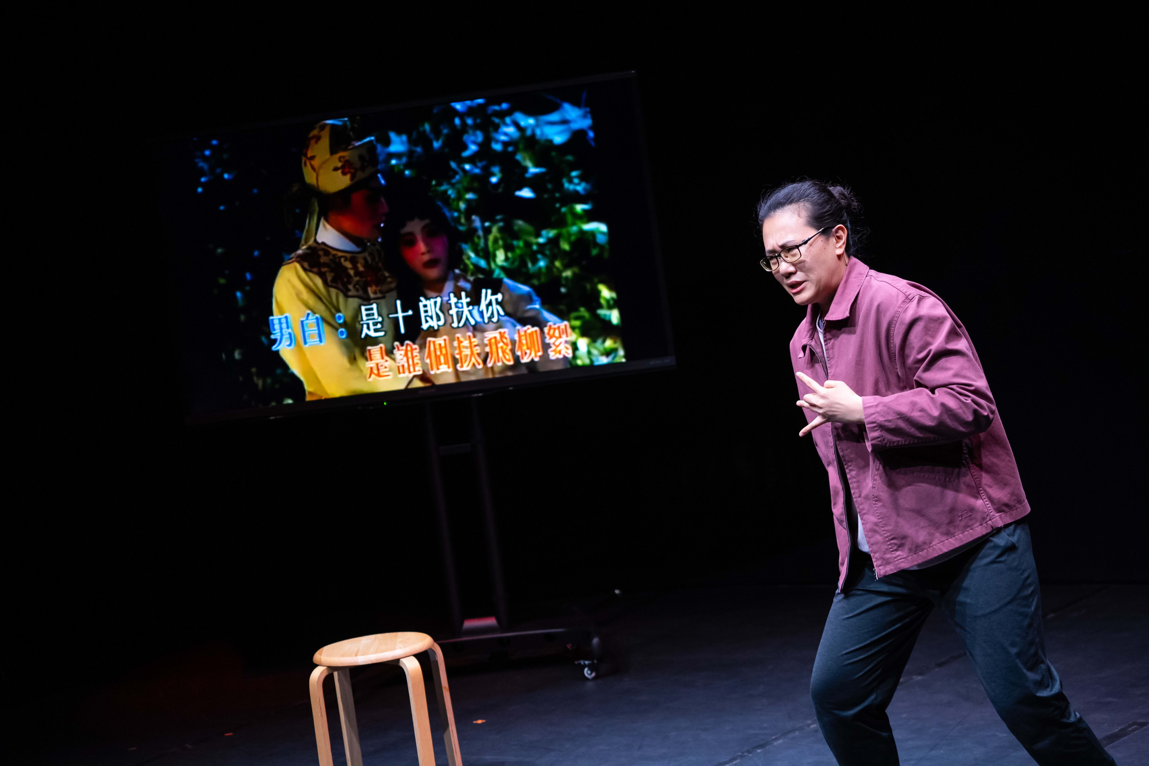 在天台製作的當代劇場作品《卡啦OK》中，演員李婉晶站在簡約的舞台上，身穿便裝，神情專注。她皺起眉頭，與身後電視屏幕上播放的經典戲曲角色霍小玉遙相呼應，舞台燈光營造出強烈的戲劇張力。表演者演繹道：「皺起眉頭，好像她就是霍小玉。」