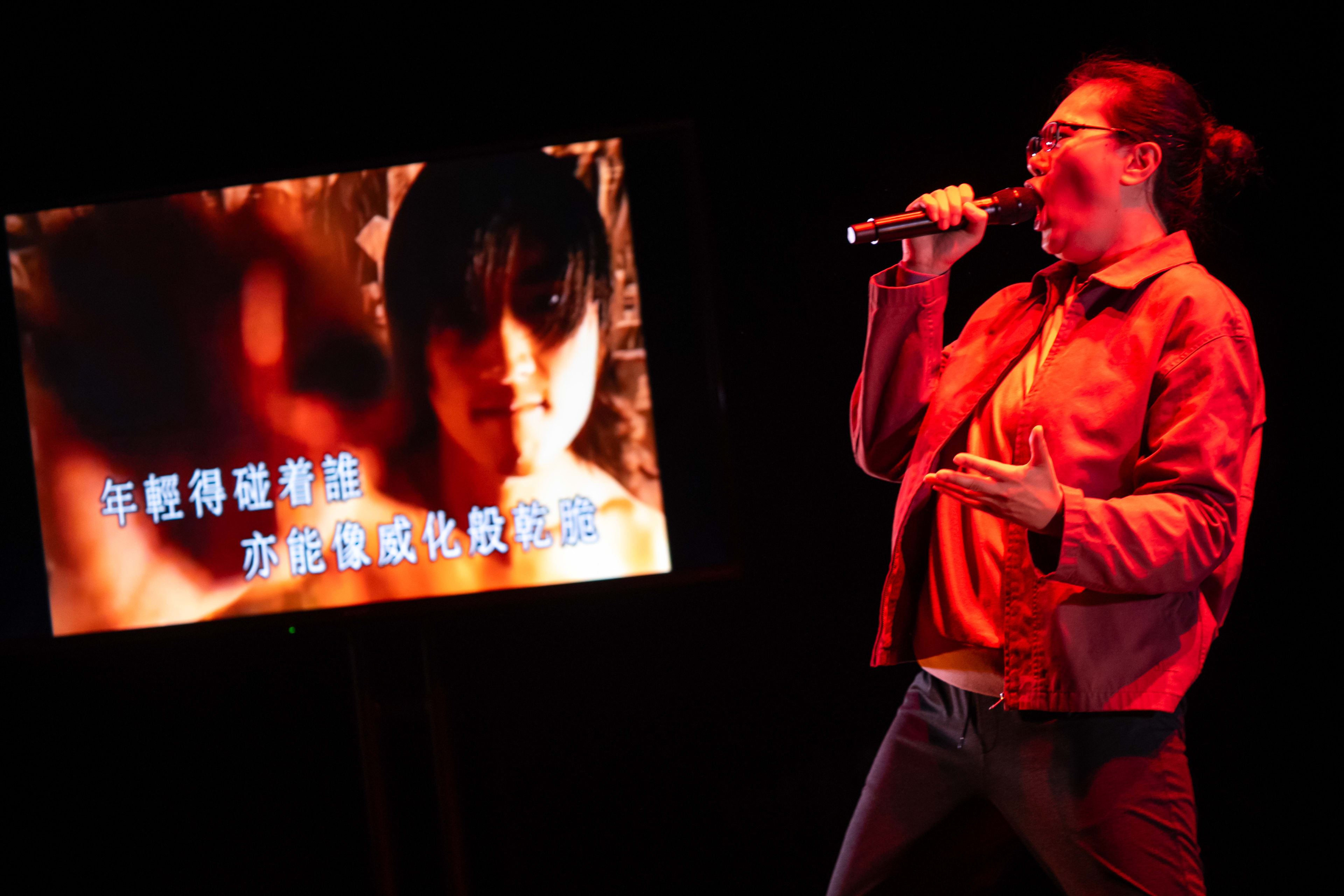 演員李婉晶於天台製作 (Rooftop Productions) 當代劇場作品《卡啦OK》中，呈現出一場充滿張力的演唱。舞台在濃郁的紅色燈光映襯下，李婉晶手持麥克風深情演繹，身後的螢幕則投射出一張青春洋溢的朦朧肖像，並伴有動態歌詞。這場香港舞台演出展現了極具感染力的現場氛圍，李婉晶唱道：「啊！年輕得碰着誰亦能像威化般乾脆。」