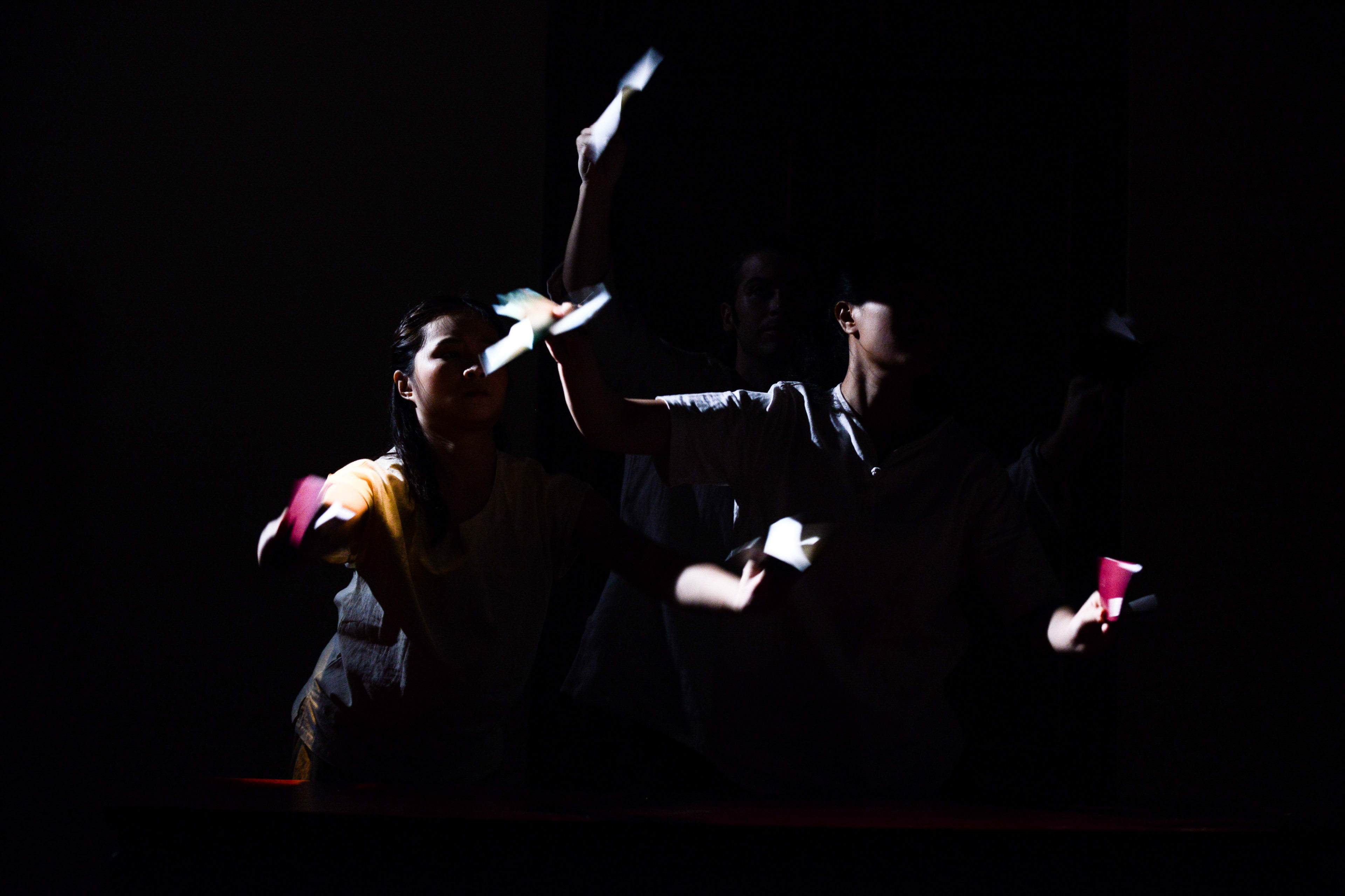 在天台製作（Rooftop Productions）當代劇場作品《牛奶與蜜糖》（Milk and Honey）的劇照中，三位演員在全黑的背景下，被幾道強烈的聚光燈照亮，呈現出極具戲劇性的光影對比。演員們動態捕捉於肢體動作之間，手中握著反光的紙質道具，營造出破碎而充滿張力的敘事氛圍。這張劇照展現了香港獨立劇場作品中常見的極簡主義美學與深刻的情感張力。《牛奶與蜜糖》