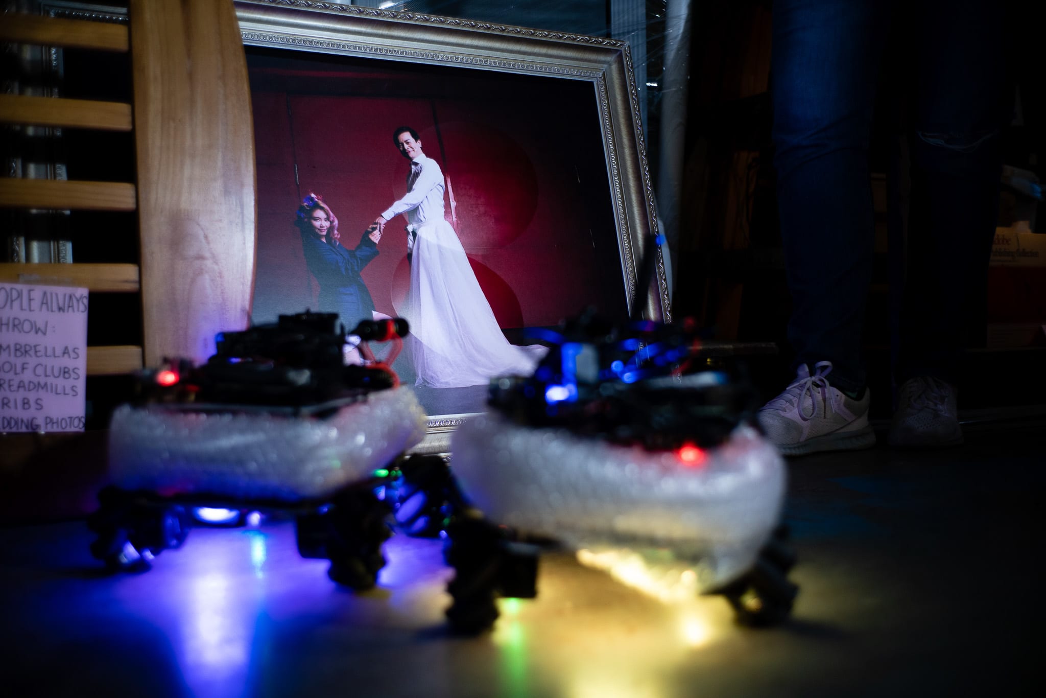 這是天台製作 Rooftop Productions 當代劇場作品《遙距在場》(Presence) 的幕後花絮，畫面中展示了一張由張貝琳 (Phoenix Cheung) 呈現的婚紗劇照，劇照後方擺放著兩個發出藍黃冷光的機械裝置，營造出香港實驗劇場獨有的沉思氛圍。演員回憶起劇中意象時說道：「婚禮照片」