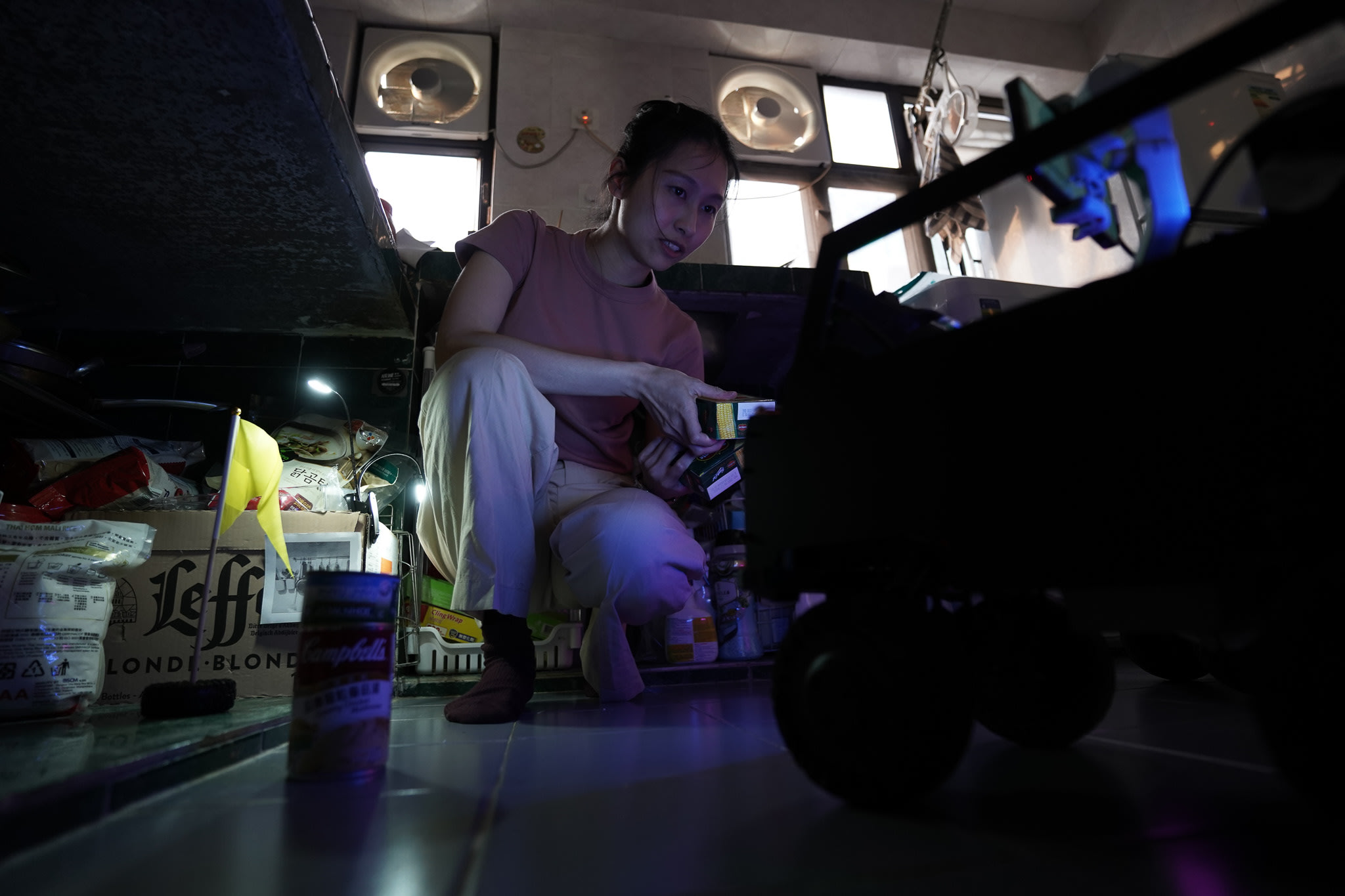 在天台製作 (Rooftop Productions) 當代劇場作品《遙距在場》(Presence) 的排練現場，演員蘇巧珊蹲在地面，專注地觀察著一件小型深色道具車。這張照片以低調的舞台燈光捕捉了這一瞬間，展現了香港實驗劇場中對細節的刻畫與親密的演繹空間。蘇巧珊在戲中說道：「脊醫話我個病好需要食魚，因為魚入面有豐富嘅omega3。」