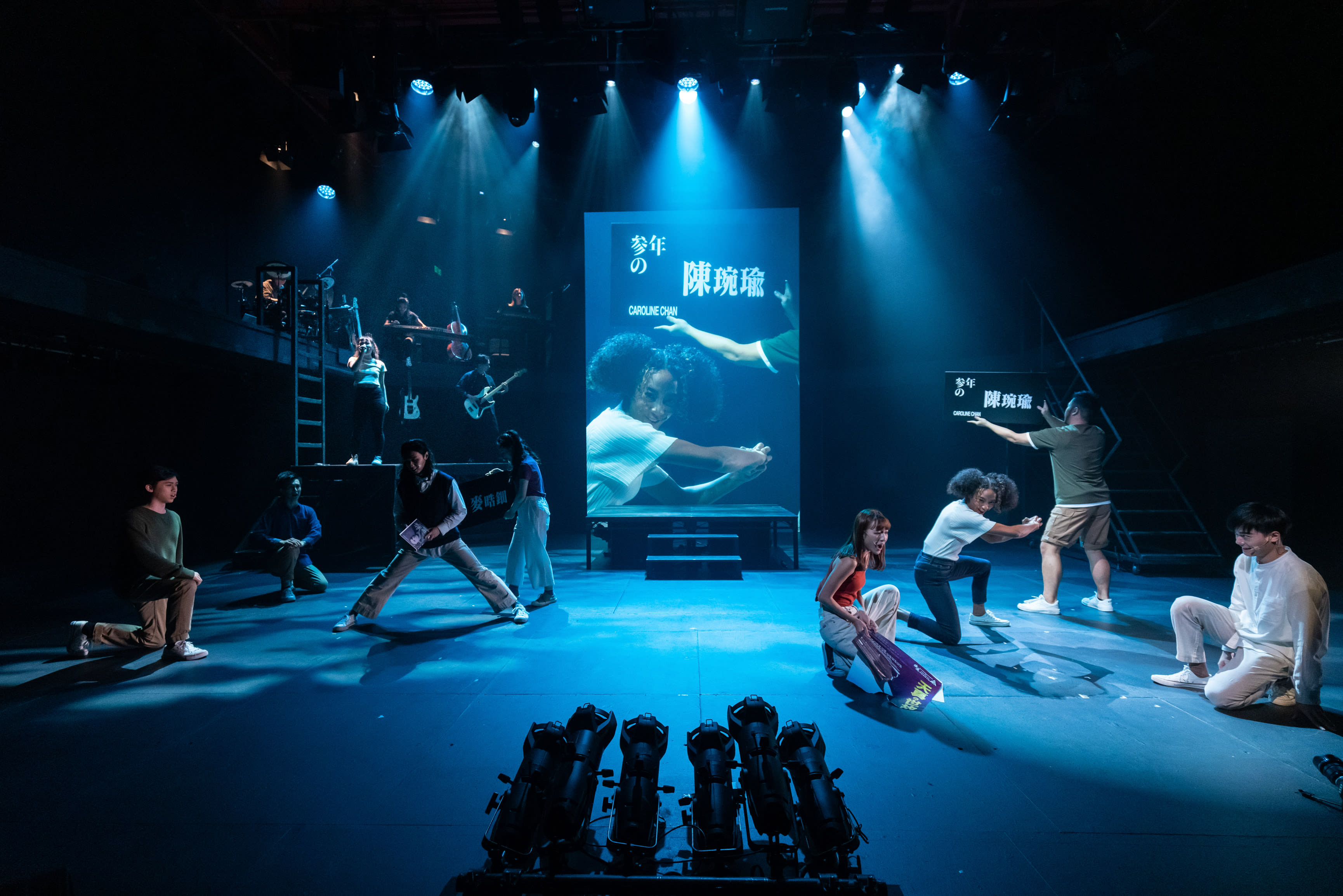 Caroline Chan as Satan looms over the stage, embodied by the cast through ritualistic movement: 'Like a cruel angel.'