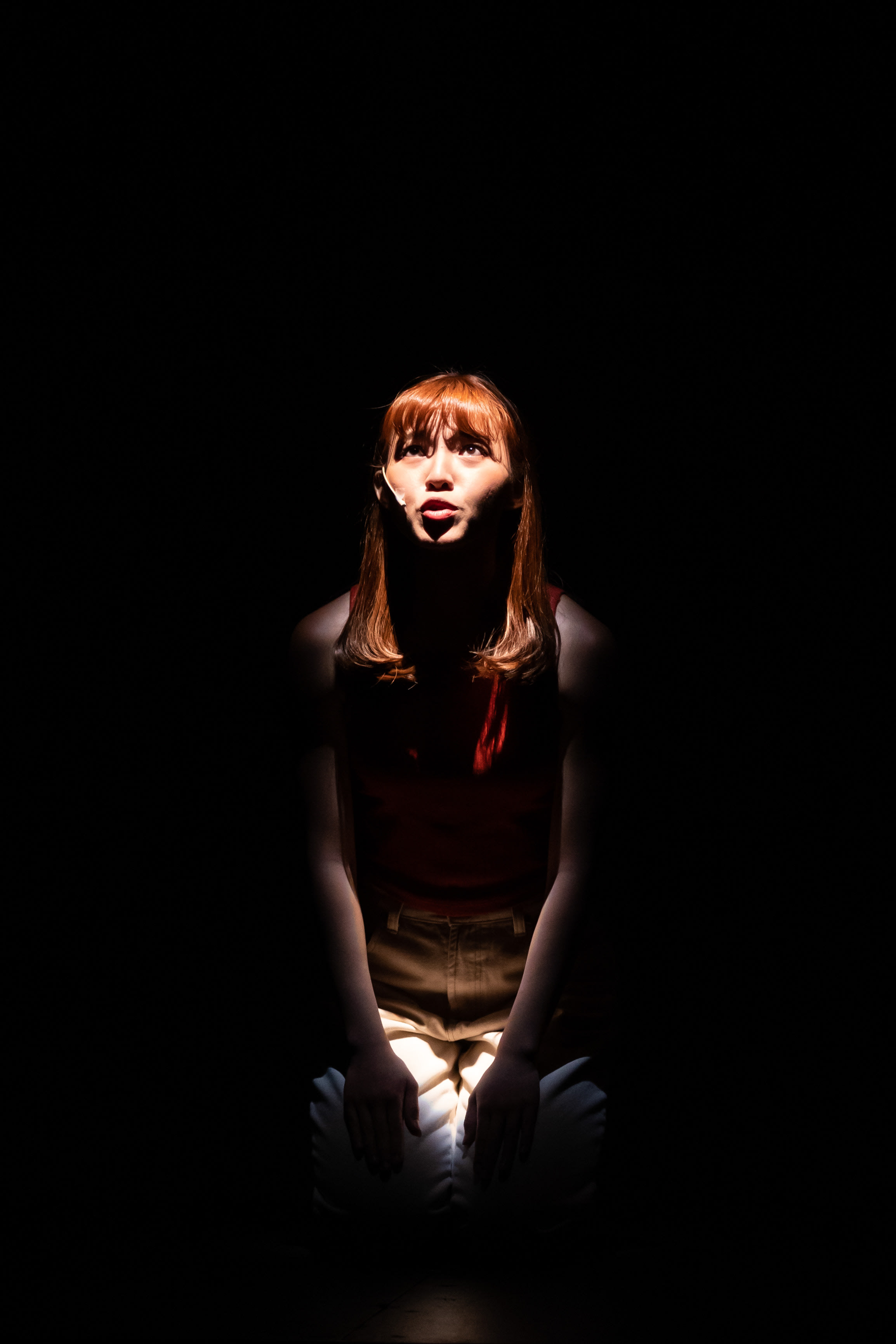 在天台製作的當代劇場作品《天真與世故之歌》（Songs of Innocence and Experience）中，演員冼樂欣被置於漆黑舞台上的一束強烈聚光燈下。她跪在地上，神情顯得脆弱而深刻，抬頭凝望上方，雙手輕放在膝蓋上。在演繹這場動人的戲劇時刻，她低吟道：「我三個月沒有跟家人吃飯。」