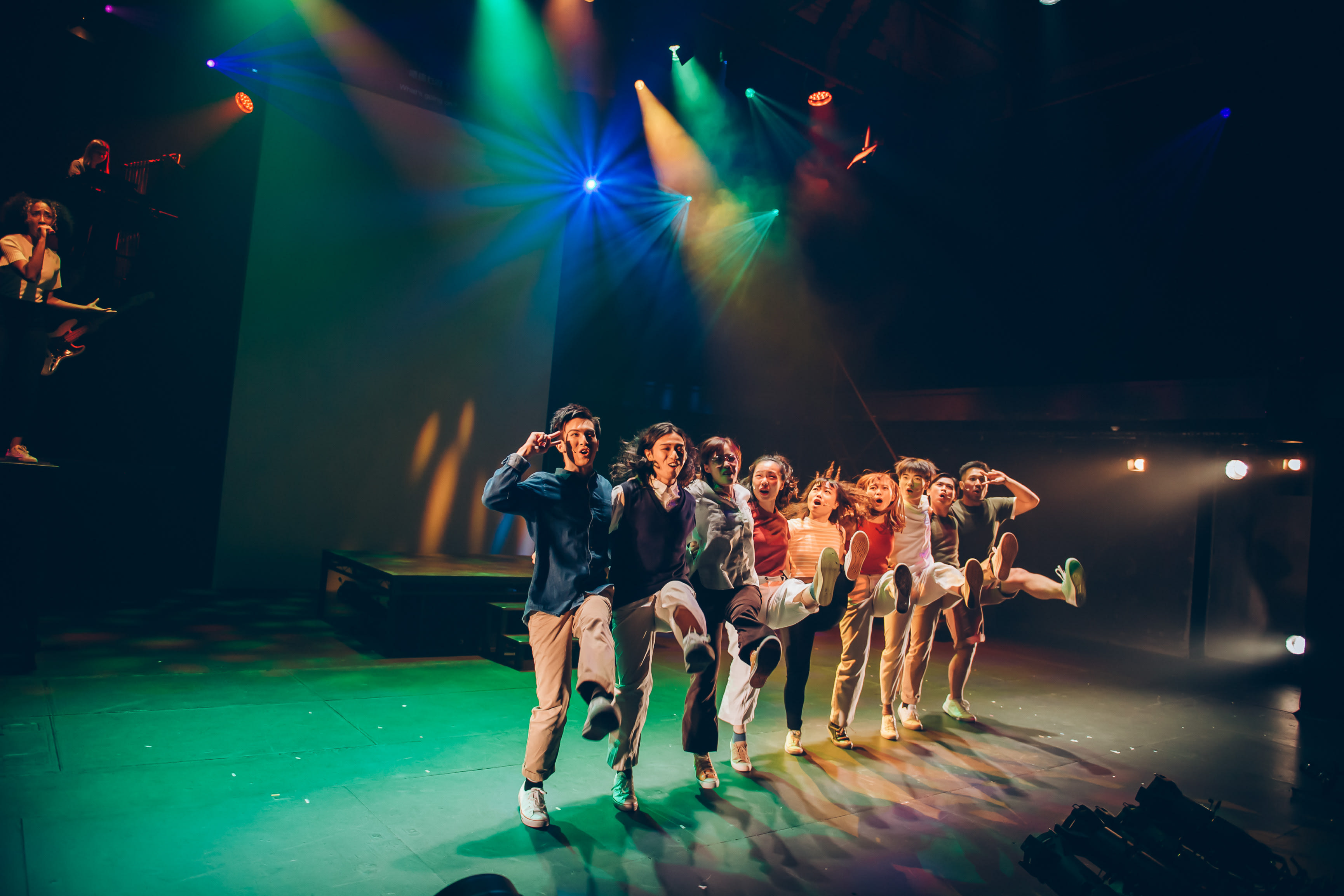 The ensemble performs a high-energy routine, navigating the balance between precision and the struggle to 'learn how to hide your feelings.'