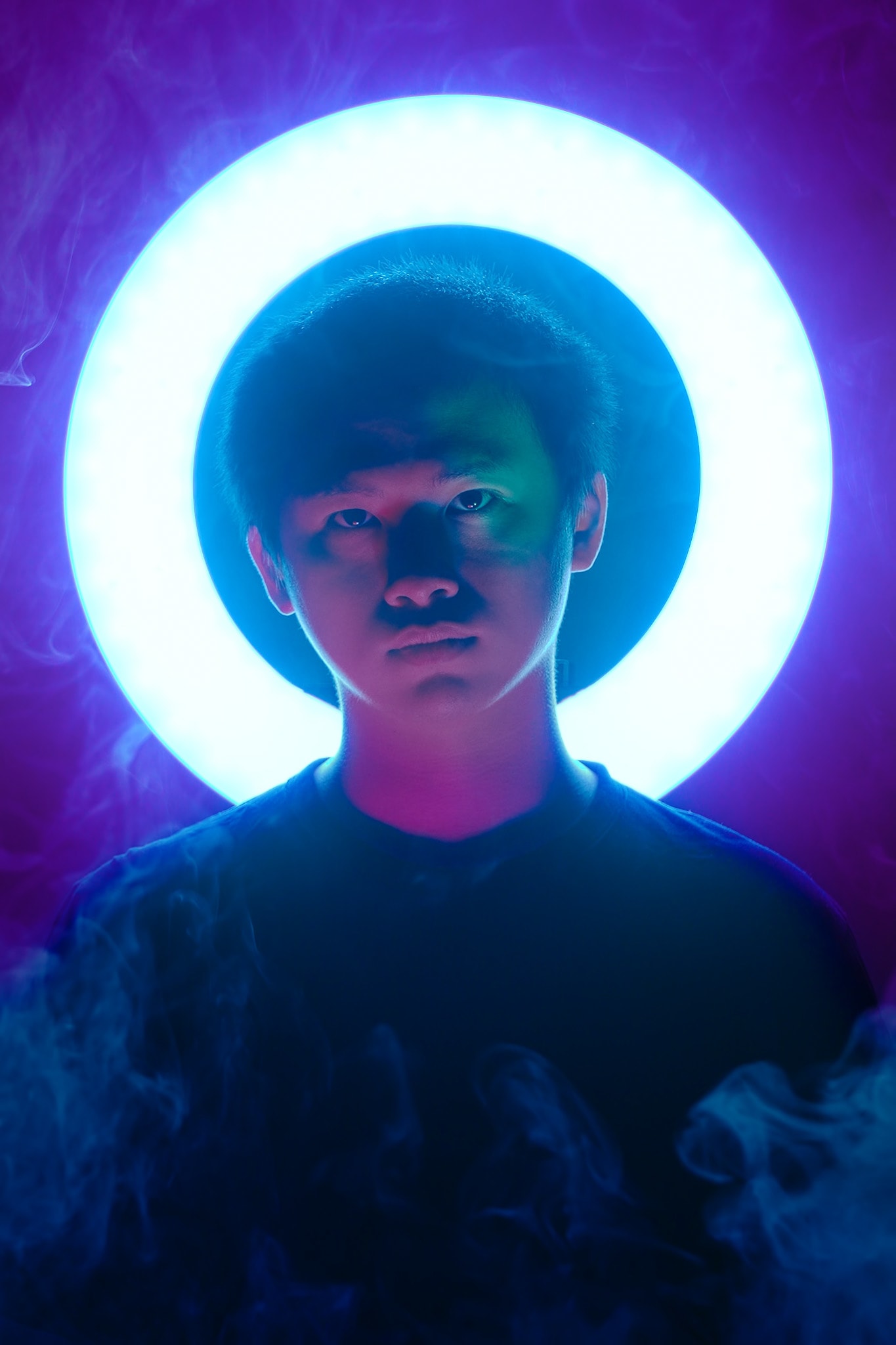 天台製作當代劇場作品《天真與世故之歌》宣傳照，由演員趙汝陽飾演瑪門。畫面以深紫色為背景，趙汝陽身後環繞著一圈明亮的圓形燈環，光影對比強烈，勾勒出他深邃且富有張力的面部神情，完美呈現香港當代劇場的藝術風格與西九文化區的演出氣息。這是一張為《天真與世故之歌》西九文化區演出拍攝的宣傳定妝照。