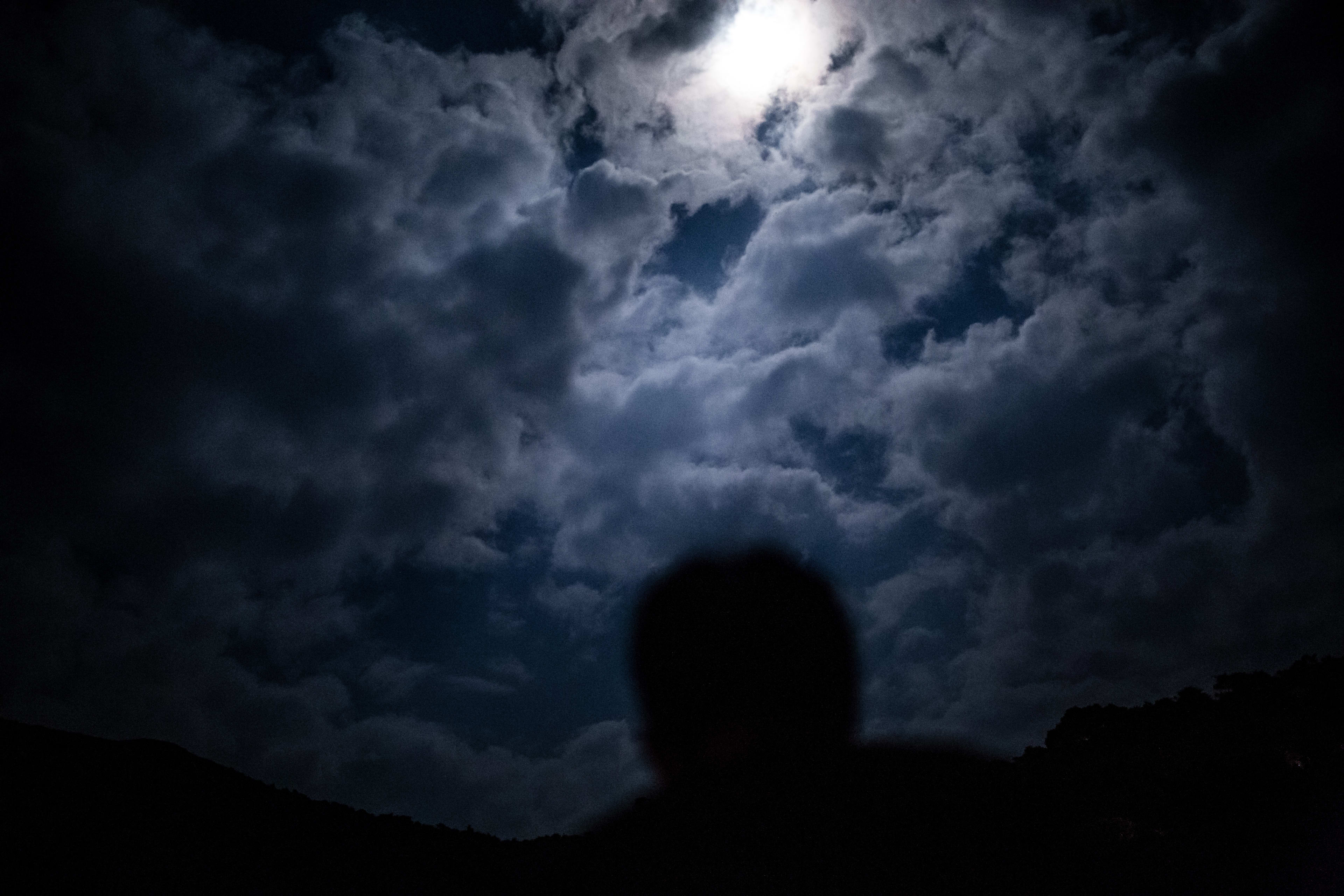 這是一張來自天台製作「當劇場走進大自然2016」的戲劇攝影，畫面中表演者的剪影與月光映照下的雲層形成強烈對比，充滿戲劇張力。此影像展現了天台製作致力於結合表演藝術與自然環境的當代劇場理念。「當劇場走進大自然2016」