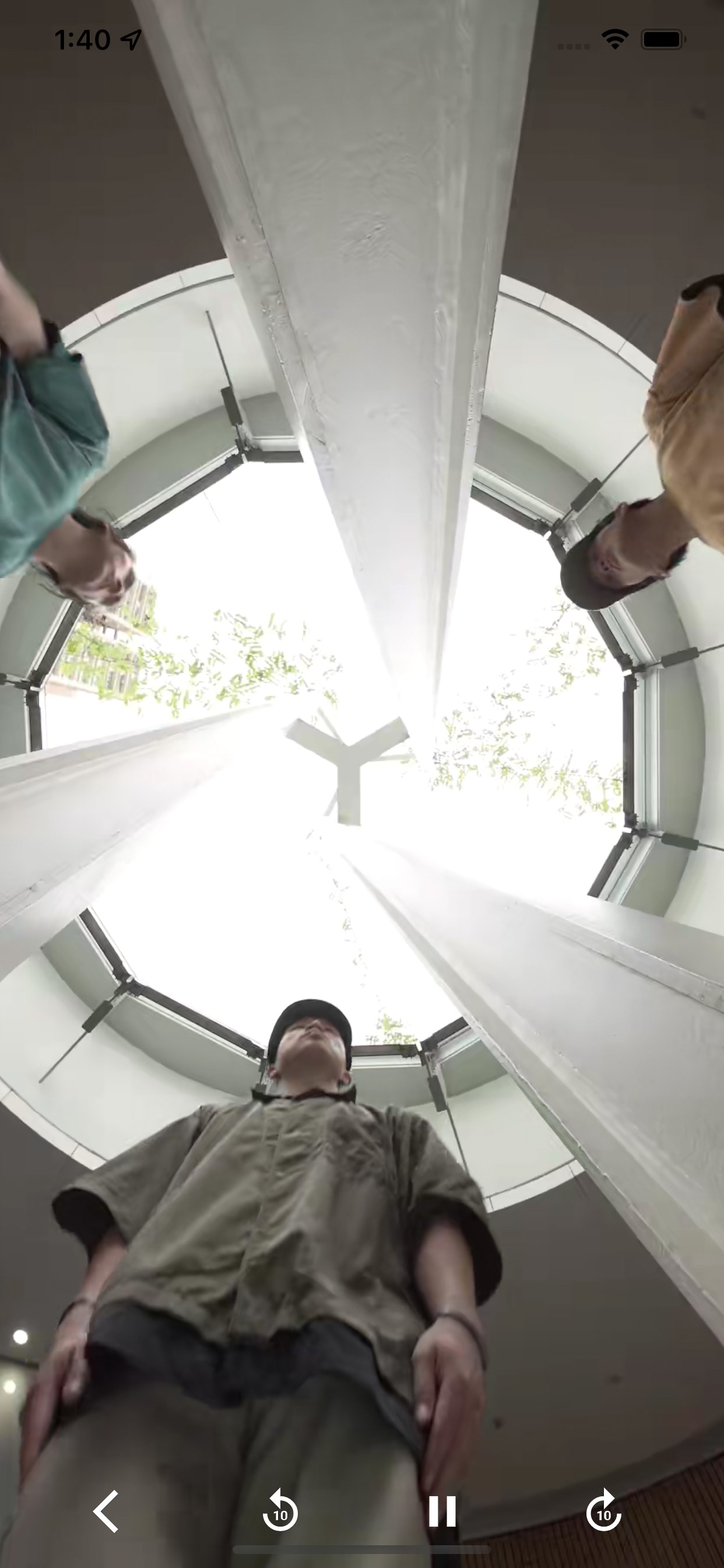 A low-angle, wide-lens screenshot from the We Still Dance app, showing three performers from the contemporary Hong Kong theatre production 《舞照跳》 looking down into the camera from a bright, circular architectural structure. The composition emphasizes the performers' connection to the stage space, capturing a moment of artistic intimacy typical of Rooftop Productions' immersive works. We Still Dance app screenshot.