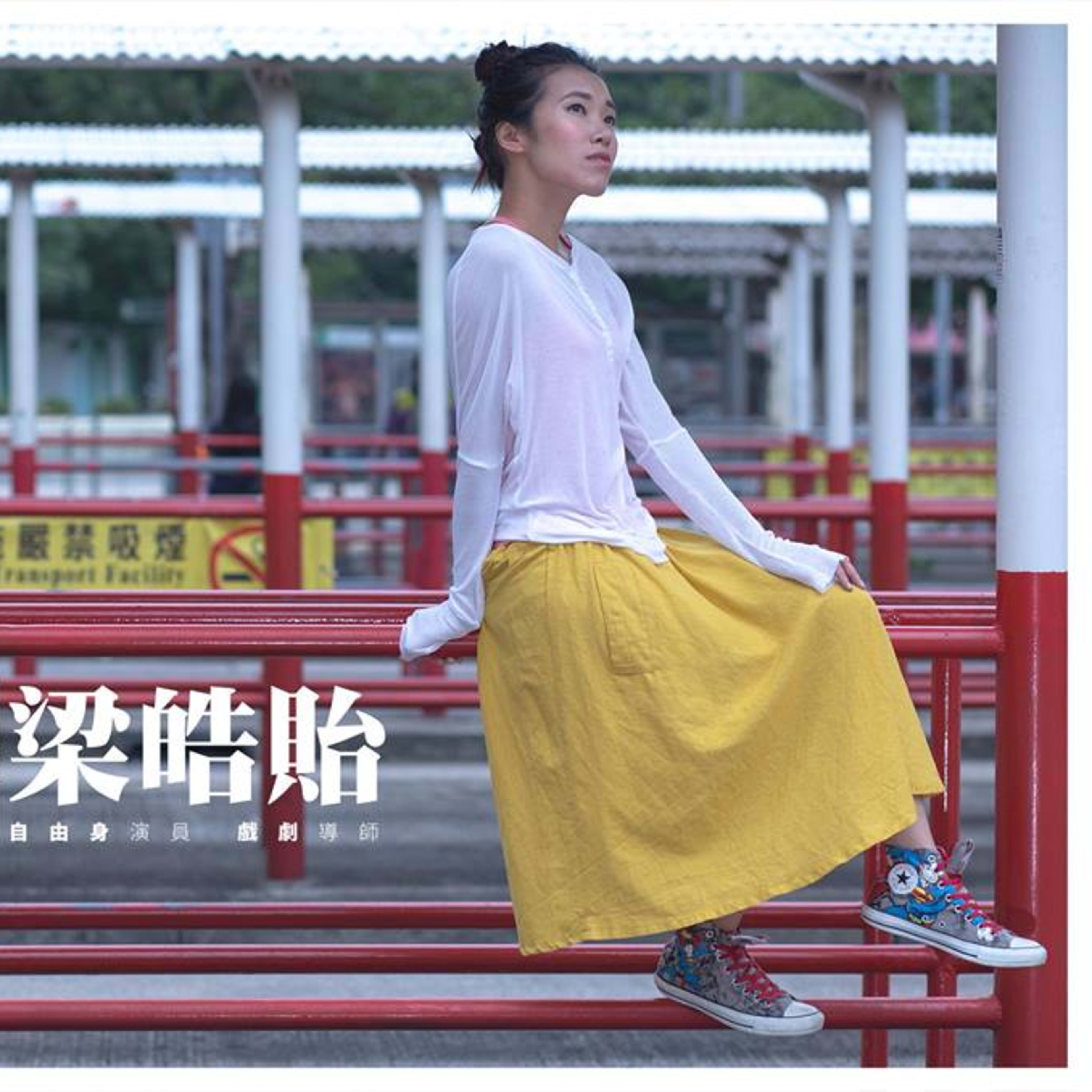 天台製作 (Rooftop Productions) 「劇場女兒」系列宣傳照，由劇場演員及戲劇導師梁皓貽擔任主角。梁皓貽身穿白色長袖上衣及黃色長裙，腳踏印花帆布鞋，坐在一處紅色巴士站欄杆上，神情淡然地望向遠方。影像將香港城市地景與當代劇場藝術相互交織，呈現出獨特的在地氣息。