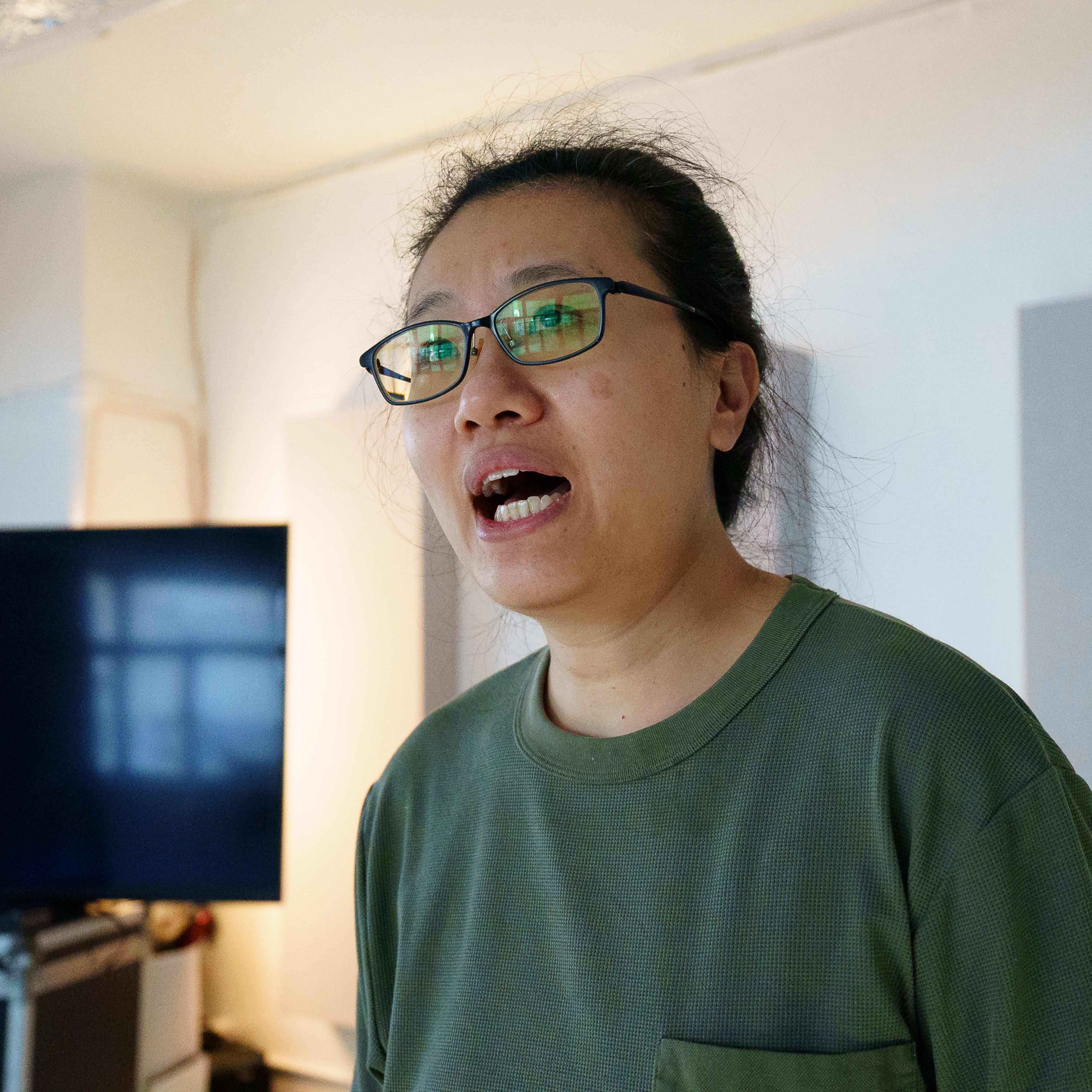 演員李婉晶（Michelle Li）於天台製作（Rooftop Productions）當代劇場作品《卡啦OK》排練期間的近照。她戴著眼鏡，身穿綠色上衣，在排練室中全神貫注地進行情感投入的排演。『《卡啦OK》排練』